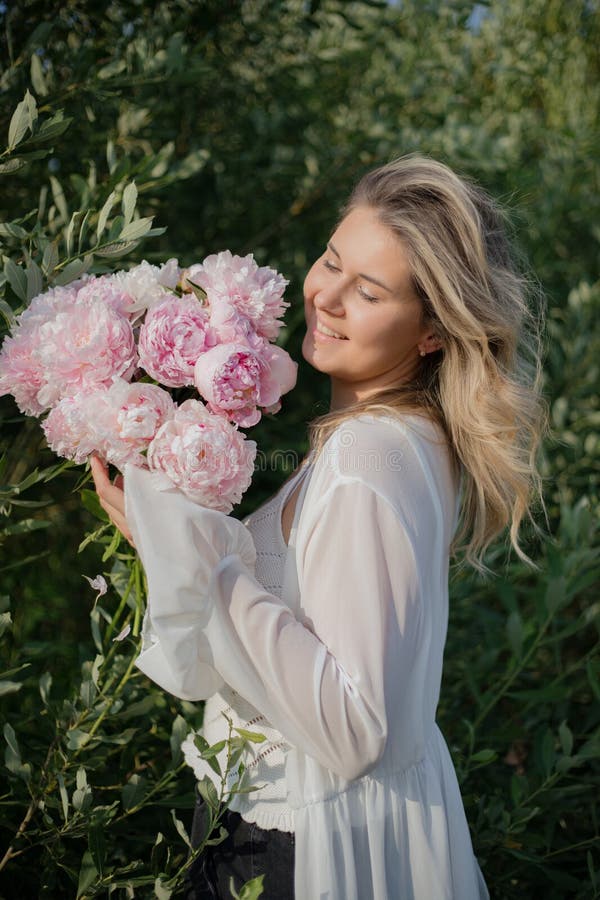 Portrait vertical de charmant fleuriste féminin avec bouquet de délicates pivoines dans la nature. positif. photographie stock