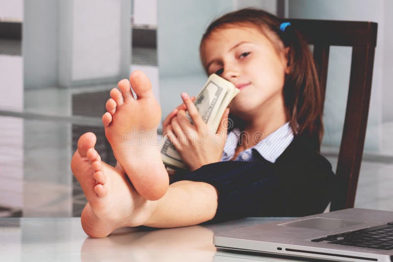 Portrait of very happy cute young business girl with bare feet on the table and counts money profit. Selective focus