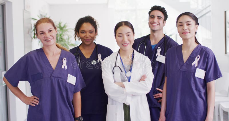 Portrait vidéo de divers médecins heureux portant des rubans cancéreux souriants dans le couloir de l'hôpital banque de vidéos