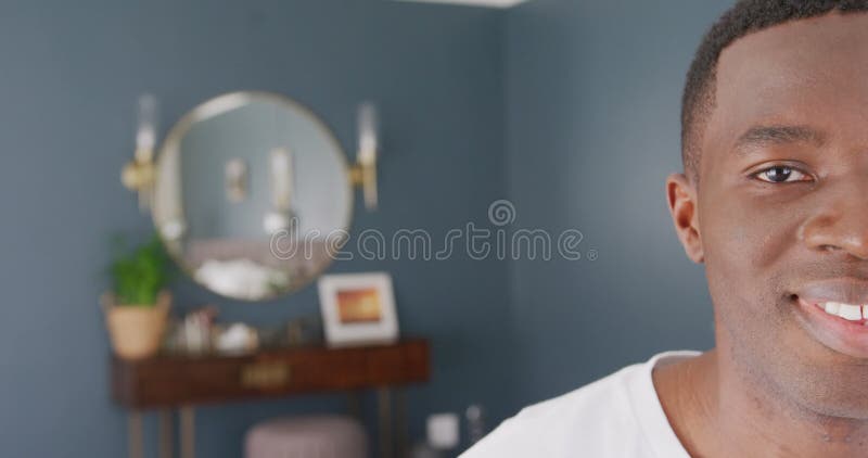 Portrait vidéo de la moitié du visage d'un afro-américain souriant chez lui avec un espace photographique banque de vidéos