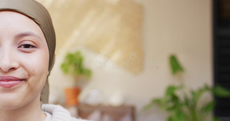 Portrait vidéo de la moitié du visage d'une femme biraciale heureuse en hijab brun souriant à la caméra photographier l'espace clips vidéos