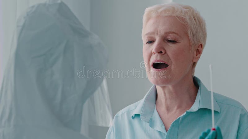 Portrait vieille femme malade dame âgée ouvre la bouche faire test pcr analyse pour coronavirus médecin travailleur en protection banque de vidéos