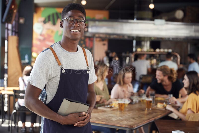 Portrait Of Waiter Serving In Busy Bar Restaurant stock photos Portrait Of Waiter Serving In Busy Bar Restaurant stock photos