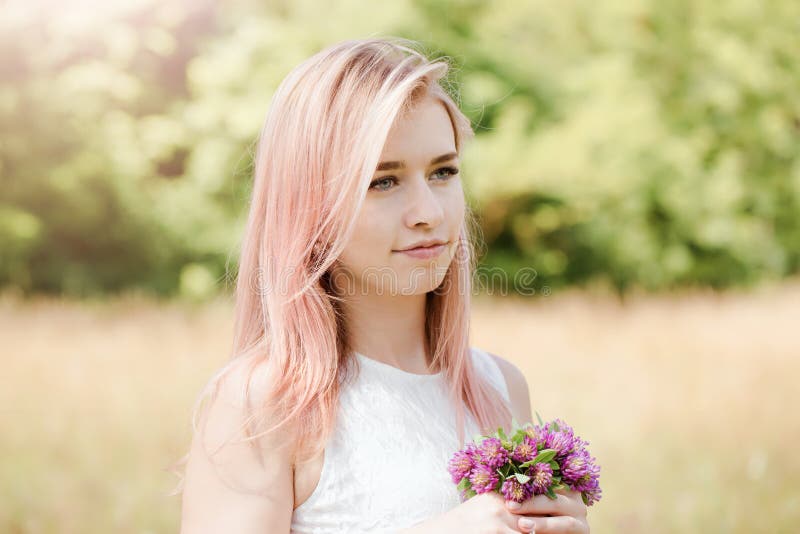 Portrait of a woman with pink hair and a clover bouquet, close-up