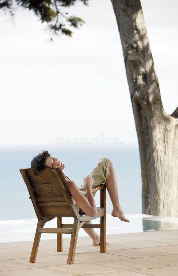 Portrait Of Woman Relaxing On Lounge Chair By Infinity Pool