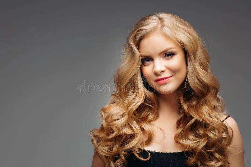 Portrait of wonderful young blonde woman with long hair looking at camera, smiling
