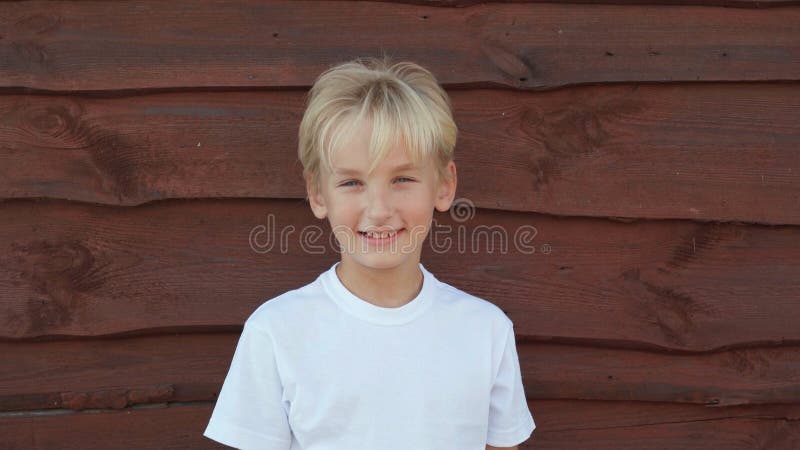 Portrait of an 8 year old boy at the wall of a barn in the village.