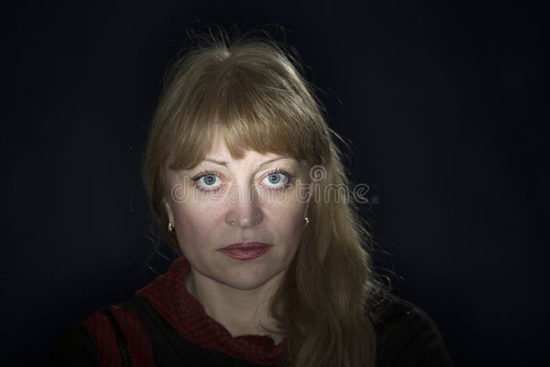 Portrait of a 50 years old blonde against a dark background