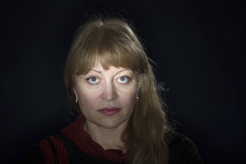 Portrait of a 50 years old blonde against a dark background