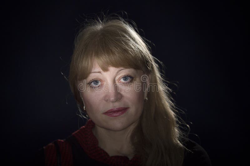 Portrait of a 50 years old blonde against a dark background