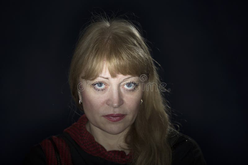 Portrait of a 50 years old blonde against a dark background