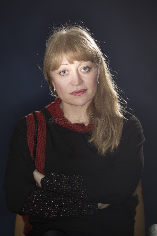 Portrait of a 50 years old blonde against a dark background