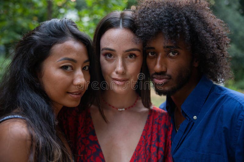 Portrait of 3 young adults together of different ethnicities, cheek to cheek, concept of diversity and respect royalty free stock photo