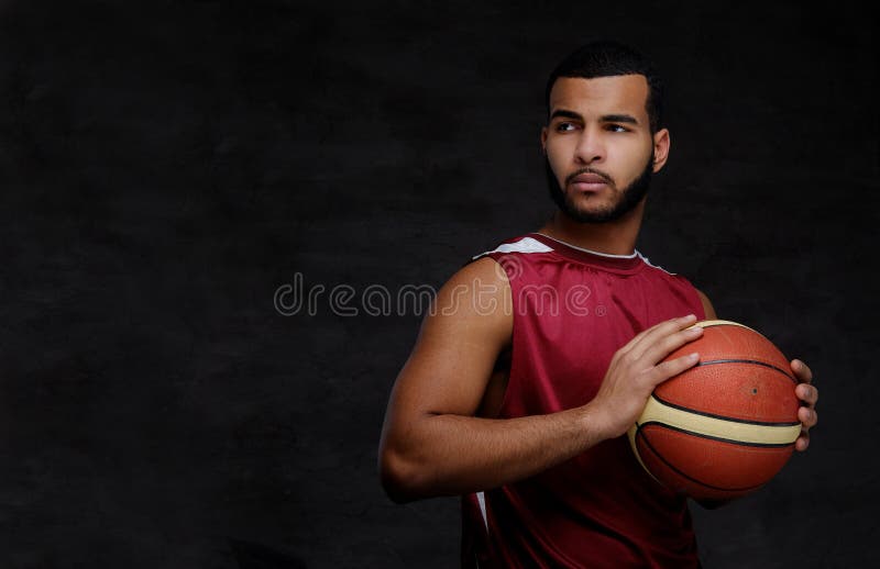 Young African-American basketball player in sportswear over dark background.