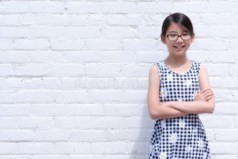 Portrait of young Asian girl against white brick wall
