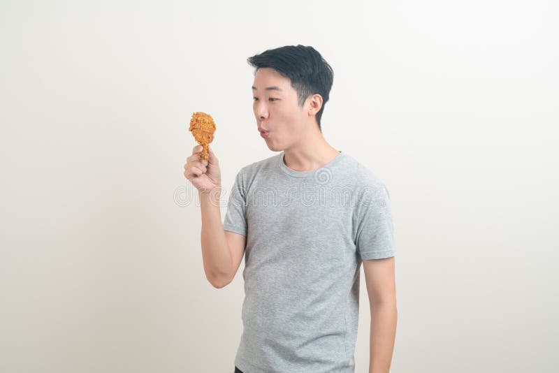 Young Asian man with fried chicken on hand stock photo