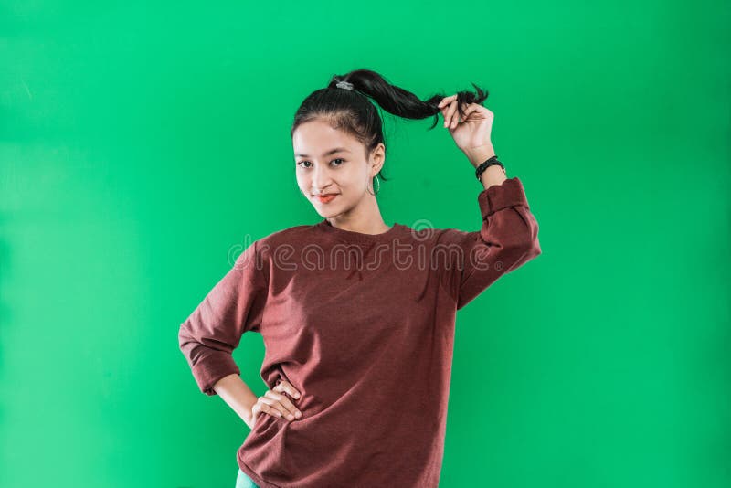 portrait young Asian woman smiling face while holding her long black hair up and looking to the camera