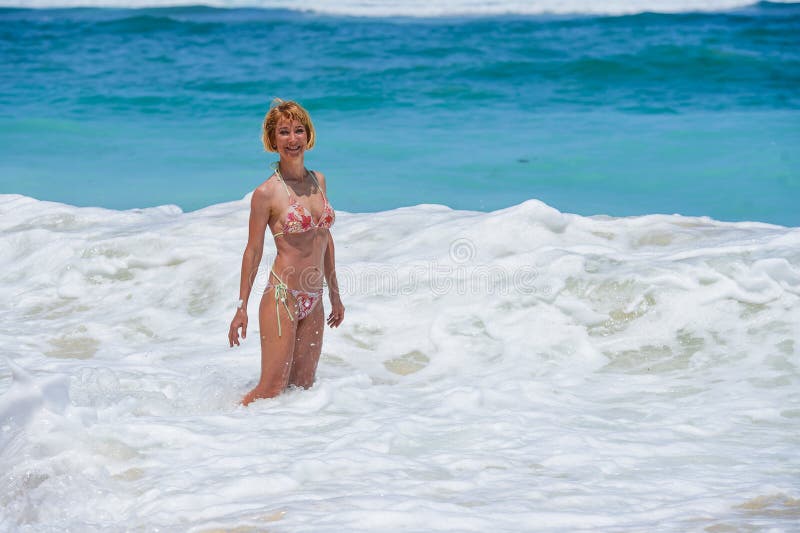 Portrait of young attractive and happy woman in bikini posing at amazing beautiful desert beach with big waves enjoying Summer ho