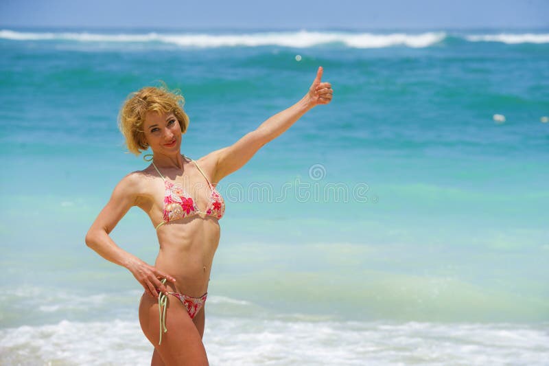 Portrait of young attractive and happy woman in bikini posing at amazing beautiful desert beach giving thumb up enjoying Summer h