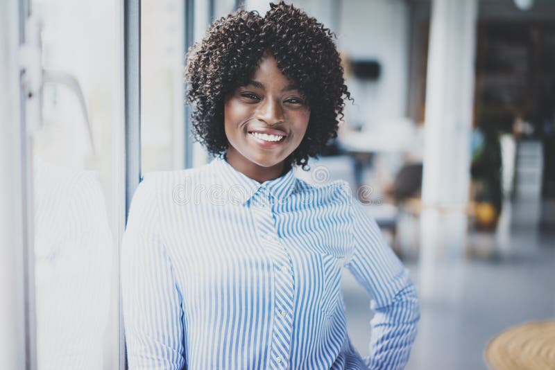 Portrait of young beautiful african woman standing with arms folded and colleagues on background.Businesswoman looking royalty free stock image Portrait of young beautiful african woman standing with arms folded and colleagues on background.Businesswoman looking royalty free stock image