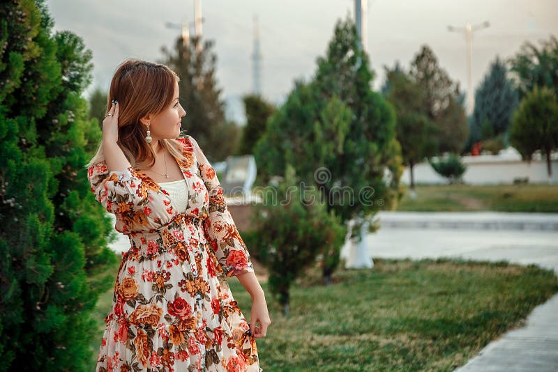 Portrait of a young beautiful Asian skinny slender woman in a floral print dress standing outside during sunset royalty free stock photography Portrait of a young beautiful Asian skinny slender woman in a floral print dress standing outside during sunset royalty free stock photography