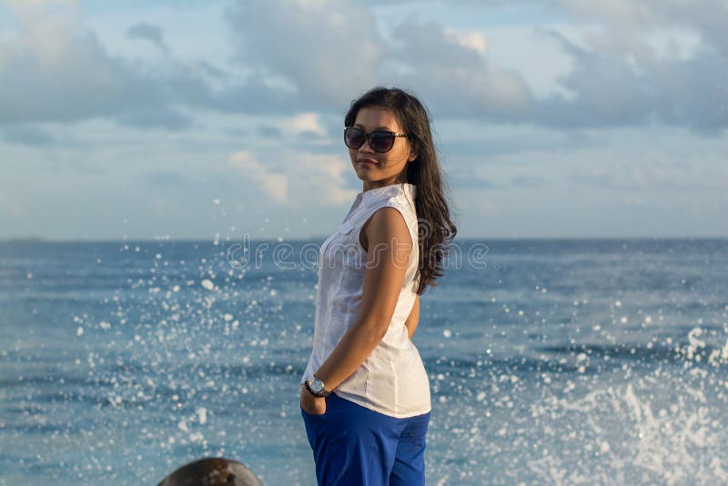 Portrait of a young beautiful asian woman in sunglasses looking back with wave splash behind royalty free stock image Portrait of a young beautiful asian woman in sunglasses looking back with wave splash behind royalty free stock image