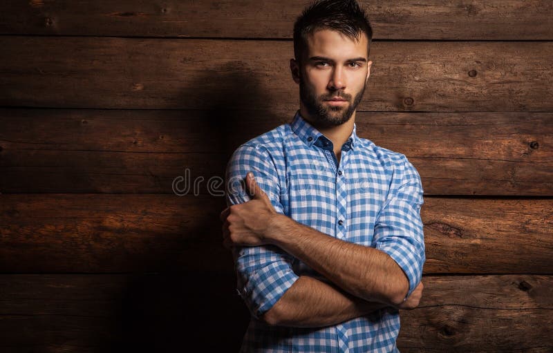 Portrait of young beautiful fashionable man against wooden wall.