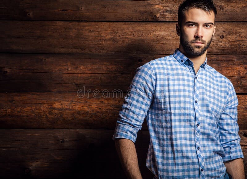 Portrait of young beautiful fashionable man against wooden wall.