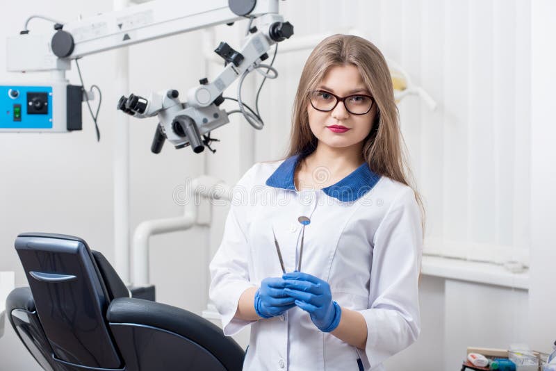 Portrait of young beautiful female dentist holding dental tools at the modern dental office royalty free stock photo Portrait of young beautiful female dentist holding dental tools at the modern dental office royalty free stock photo