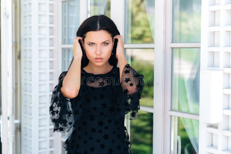 Portrait of a young beautiful girl m black dress-mesh gazing steadily into the camera. The model runs long black hair