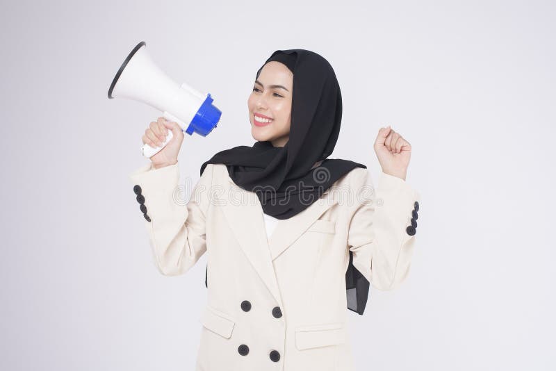 A portrait of young beautiful muslim woman in suit using megaphone to announce over isolated white background studio