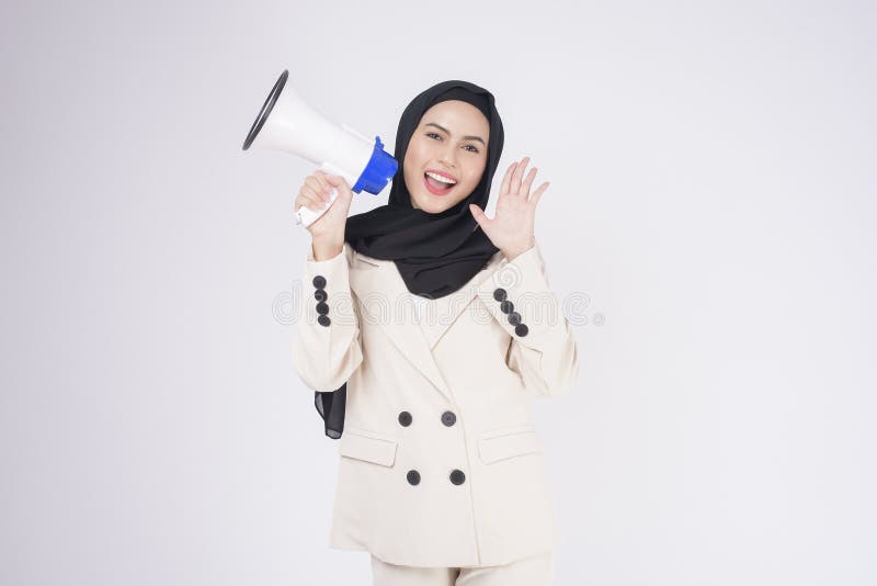 A portrait of young beautiful muslim woman in suit using megaphone to announce over isolated white background studio