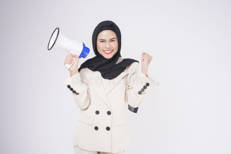 A portrait of young beautiful muslim woman in suit using megaphone to announce over isolated white background studio
