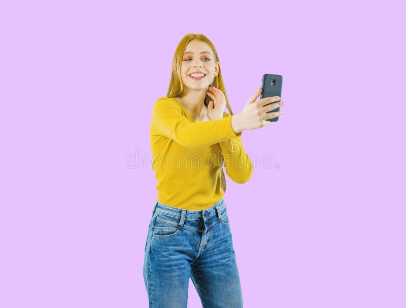 Portrait of a young beautiful red-haired woman playfully smiling and making selfies, emotions, shooting on an isolated