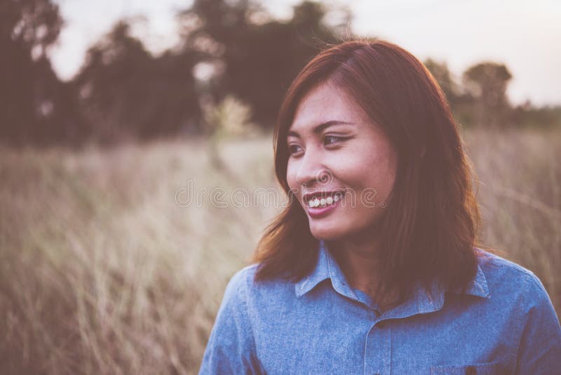 Portrait of young beautiful smile woman in sunset. Vintage filter style. Happy woman in field