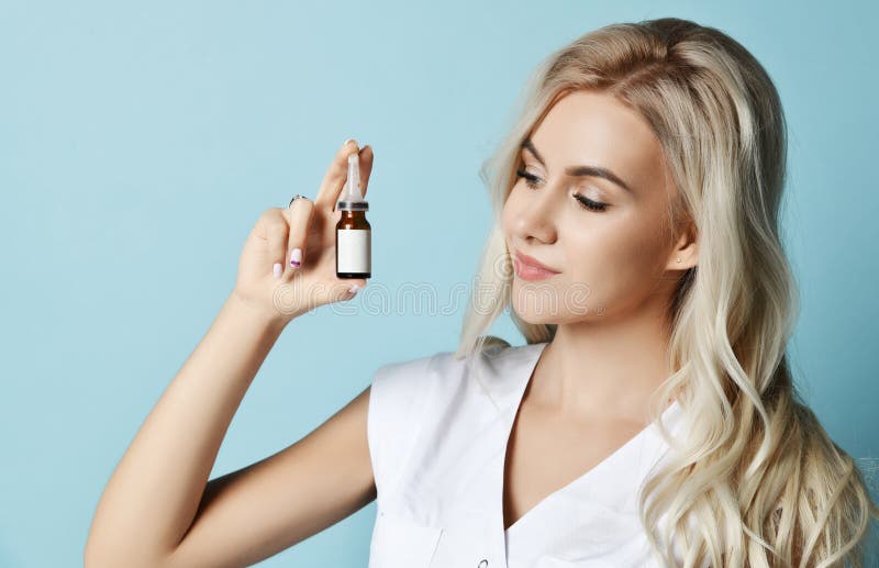 Portrait of young beautiful smiling sexy blond woman in white clothing holding small beauty ampoule in hands