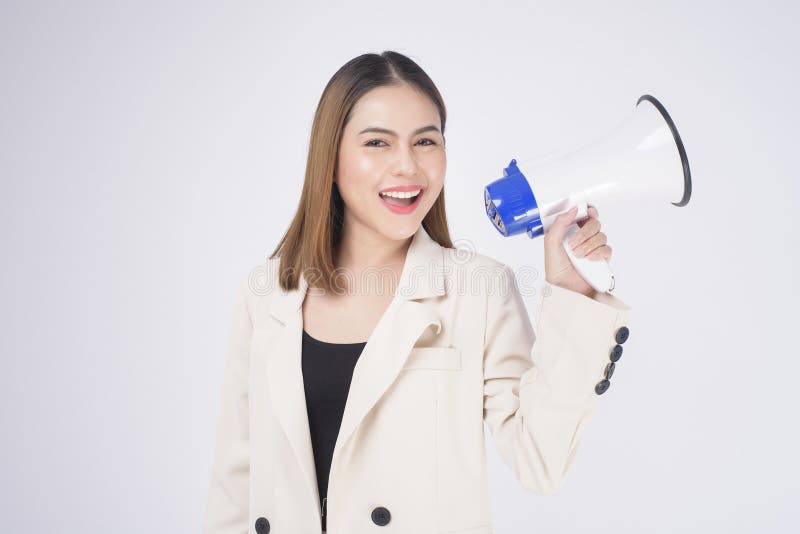 A portrait of young beautiful smiling woman in suit using megaphone to announce over isolated white background studio