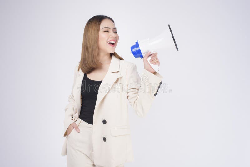 A portrait of young beautiful smiling woman in suit using megaphone to announce over isolated white background studio