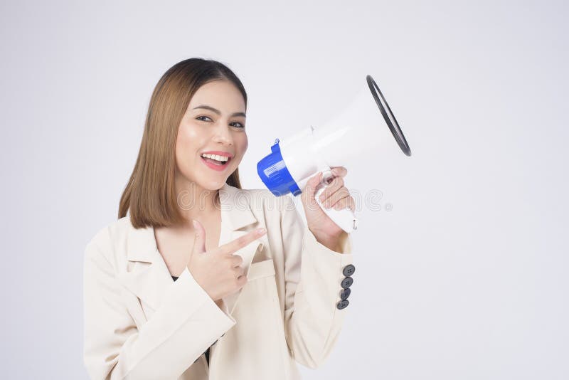 A portrait of young beautiful smiling woman in suit using megaphone to announce over isolated white background studio