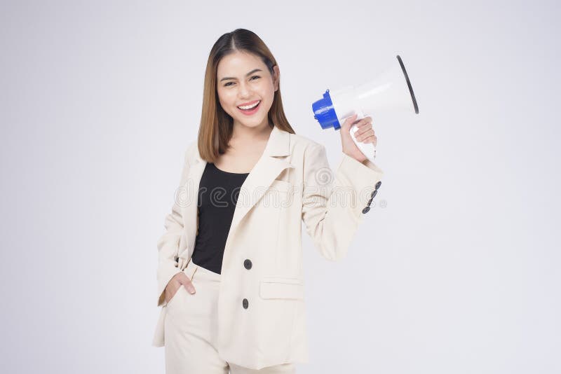 A portrait of young beautiful smiling woman in suit using megaphone to announce over isolated white background studio