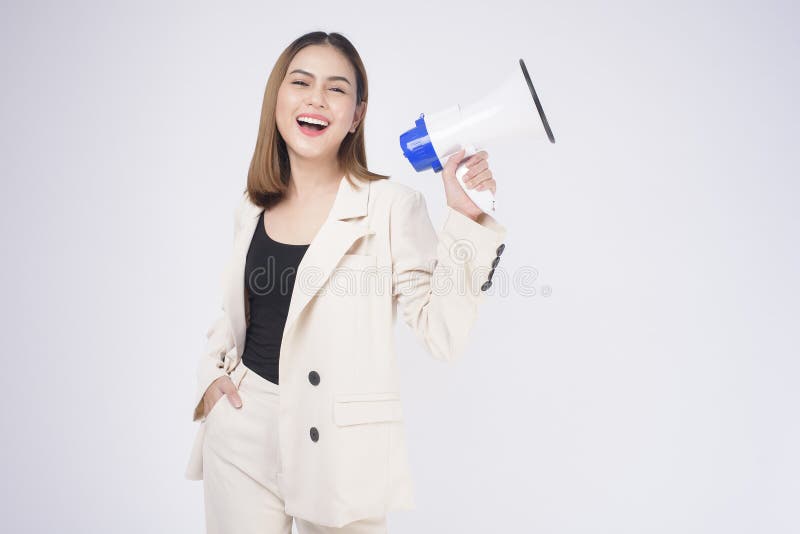 A portrait of young beautiful smiling woman in suit using megaphone to announce over isolated white background studio