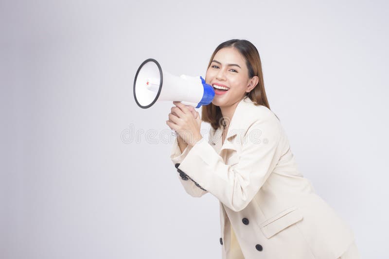 A portrait of young beautiful smiling woman in suit using megaphone to announce over isolated white background studio