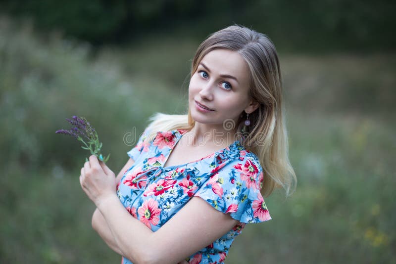 Portrait of young beautiful woman in flower vintage dress holding flowers in her hands