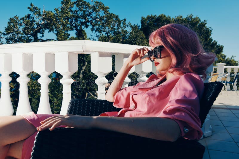 portrait of a young beautiful woman pink dress sits on the terrace sunny day