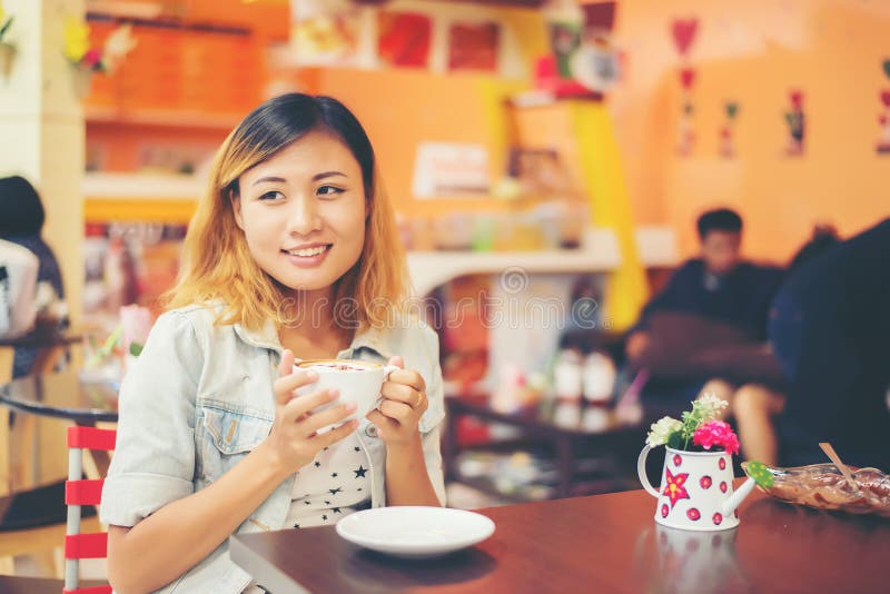 Portrait of Young Beautiful Woman Sitting in a Cafe Holding Hot Stock