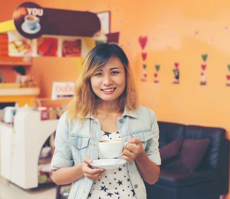 Portrait of Young Beautiful Woman Sitting in a Cafe Holding Hot Stock
