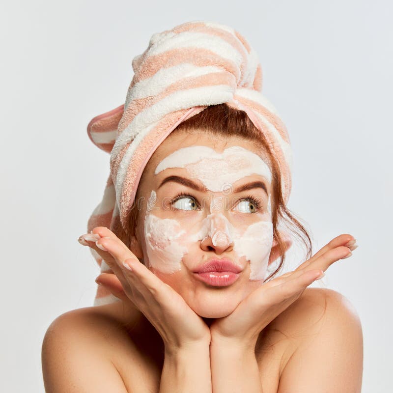 Portrait Of Young Beautiful Woman With Towel On Head After Shower Applying Clay Face Mask