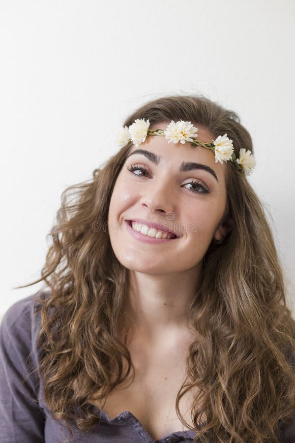 portrait of a young beautiful woman wearing a flowers wreath. She is smiling, indoors. Lifestyle. Vertical view royalty free stock photo portrait of a young beautiful woman wearing a flowers wreath. She is smiling, indoors. Lifestyle. Vertical view royalty free stock photo