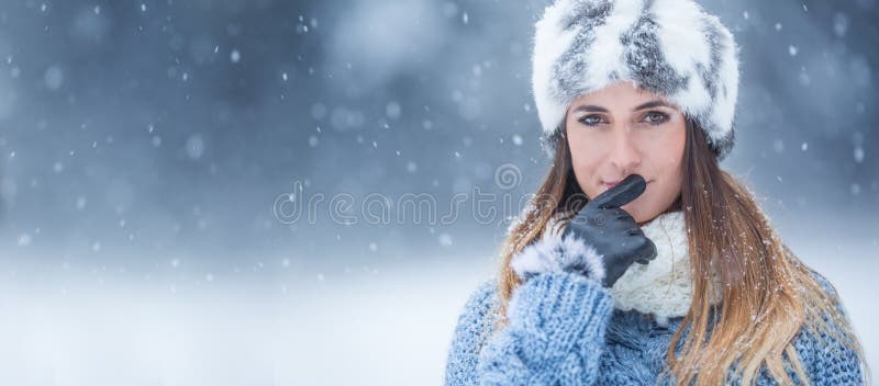 Portrait of young beautiful woman in winter clothes and strong snowing