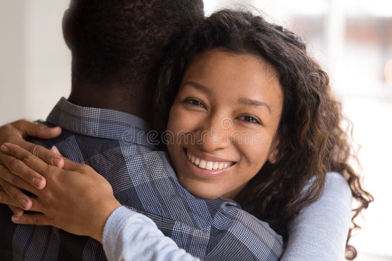 Portrait of young black smiling wife embracing husband